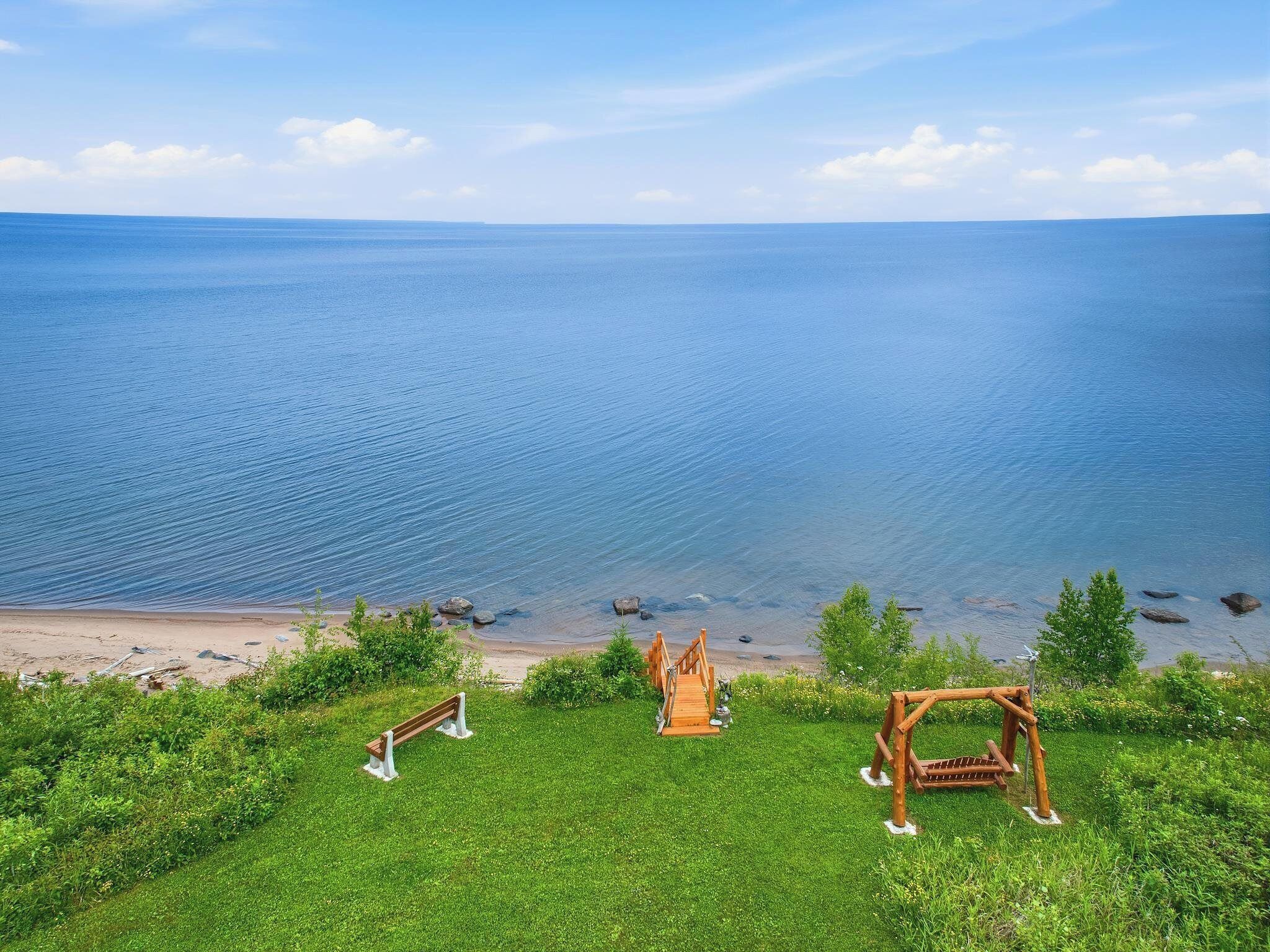 A beach with a wooden bench and a wooden structure, overlooking a calm sea.