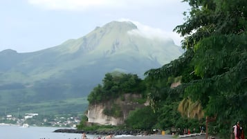 A beach with a mountain in the background, a clear sky, and a few people.
