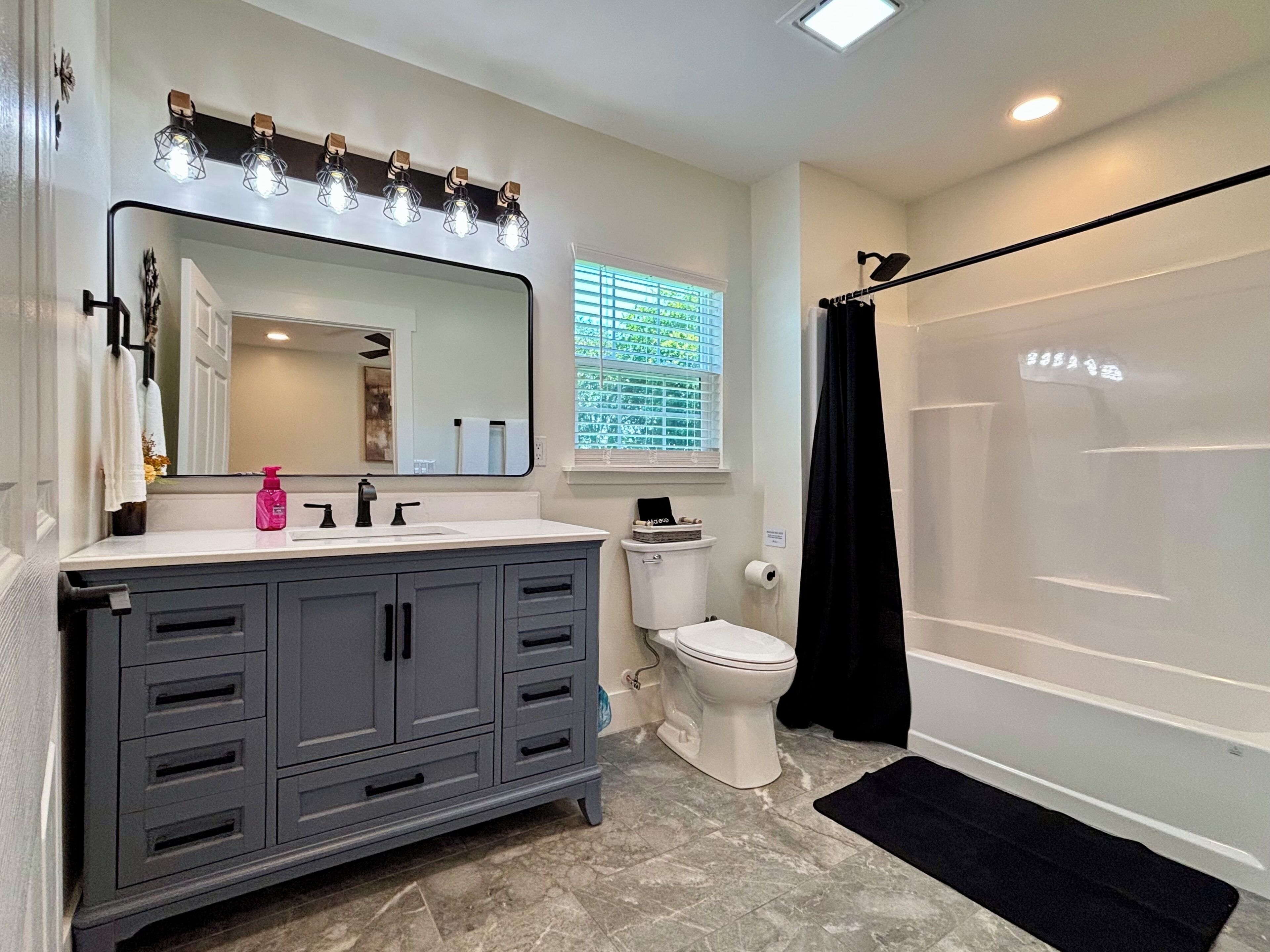 A bathroom with a vanity, toilet, and shower.