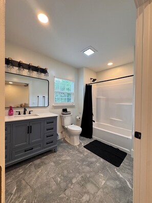 Une salle de bain comprenant des toilettes, un lavabo, un meuble-lavabo et une baignoire.