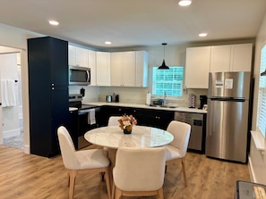 A modern kitchen with white cabinets, stainless steel appliances, and a round dining table with chairs.