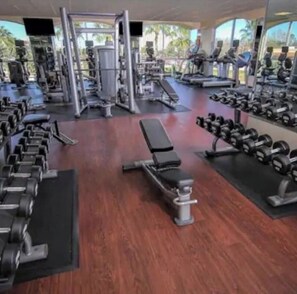 A gym with various exercise equipment, including dumbbells, benches, and cardio machines. - Spacious Apt with Balcony or Terrace and Jacuzzi bath 15mins from Universal (Orlando)