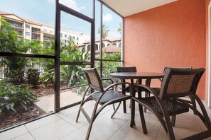 A balcony with a table and chairs, a view of a building, and a garden. - Spacious Apt with Balcony or Terrace and Jacuzzi bath 15mins from Universal (Orlando)
