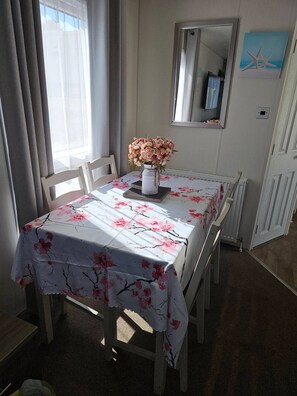 Ein Essbereich mit einem Tisch für zwei Personen, einer Blumenvase und einem Spiegel an der Wand.
