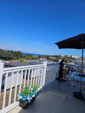 A deck with a white railing, a table with chairs, and a potted plant with flowers. - The Bay View Sea Views, Pool, Parking & Sleeps 6 (Paignton)