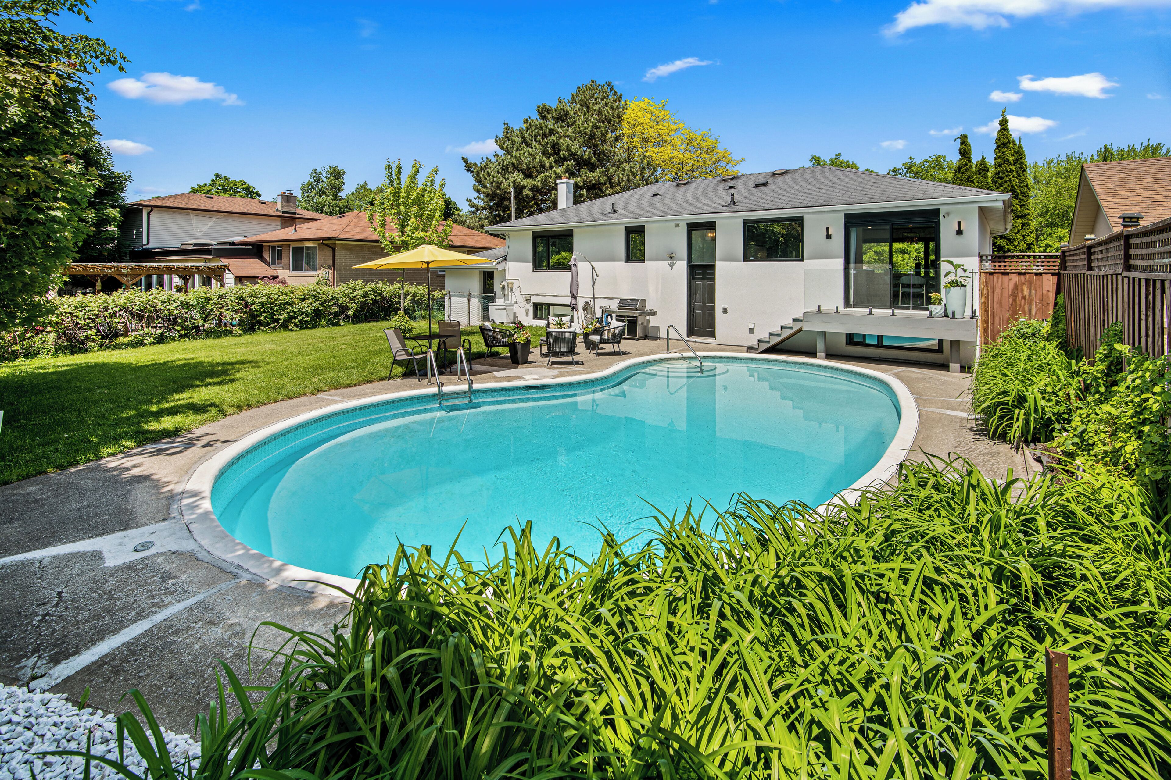 A residential swimming pool with a house in the background.