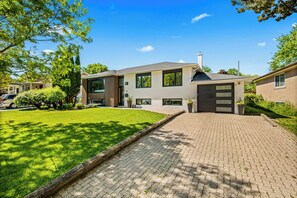 A modern two-story house with a paved driveway and a well-maintained lawn. - Beautifully Remodeled 2 Bedroom Basement Apartment (Toronto)