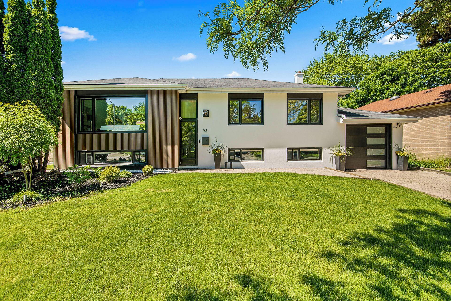 A modern two-story house with a well-maintained lawn, large windows, and a brick exterior.
