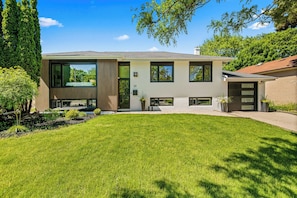 A modern two-story house with a well-maintained lawn, large windows, and a brick exterior. - Beautifully Remodeled 2 Bedroom Basement Apartment (Toronto)