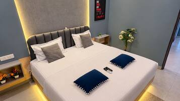 A modern bedroom with a bed, bedside tables, an air conditioning unit, a wall-mounted fan, and a poster.