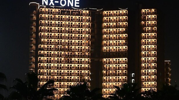 Um edifício de hotel com vários andares e um grande letreiro 'NX-ONE' no topo.