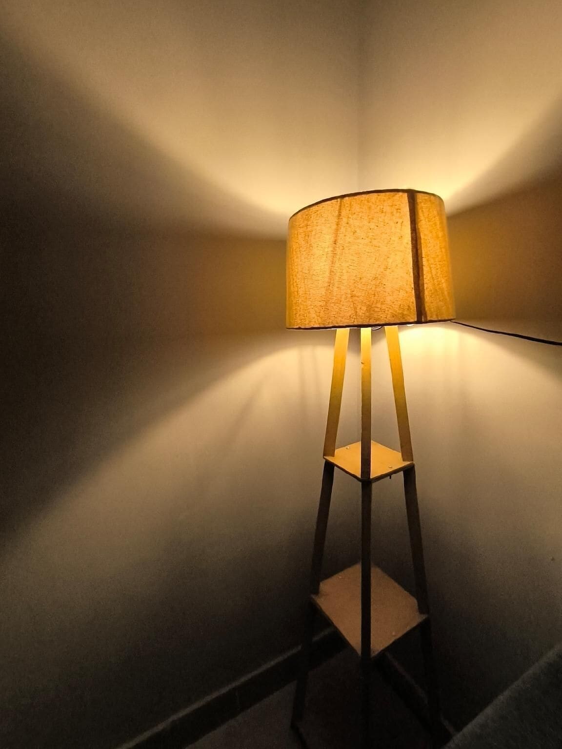 A floor lamp with a fabric shade in a room with plain walls.