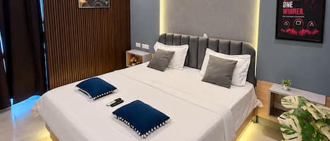 A modern bedroom with a large bed, a ceiling fan, an air conditioning unit, a wall-mounted artwork, and a motivational poster.