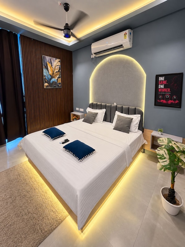 A modern bedroom with a large bed, a ceiling fan, an air conditioning unit, a wall-mounted artwork, and a motivational poster.