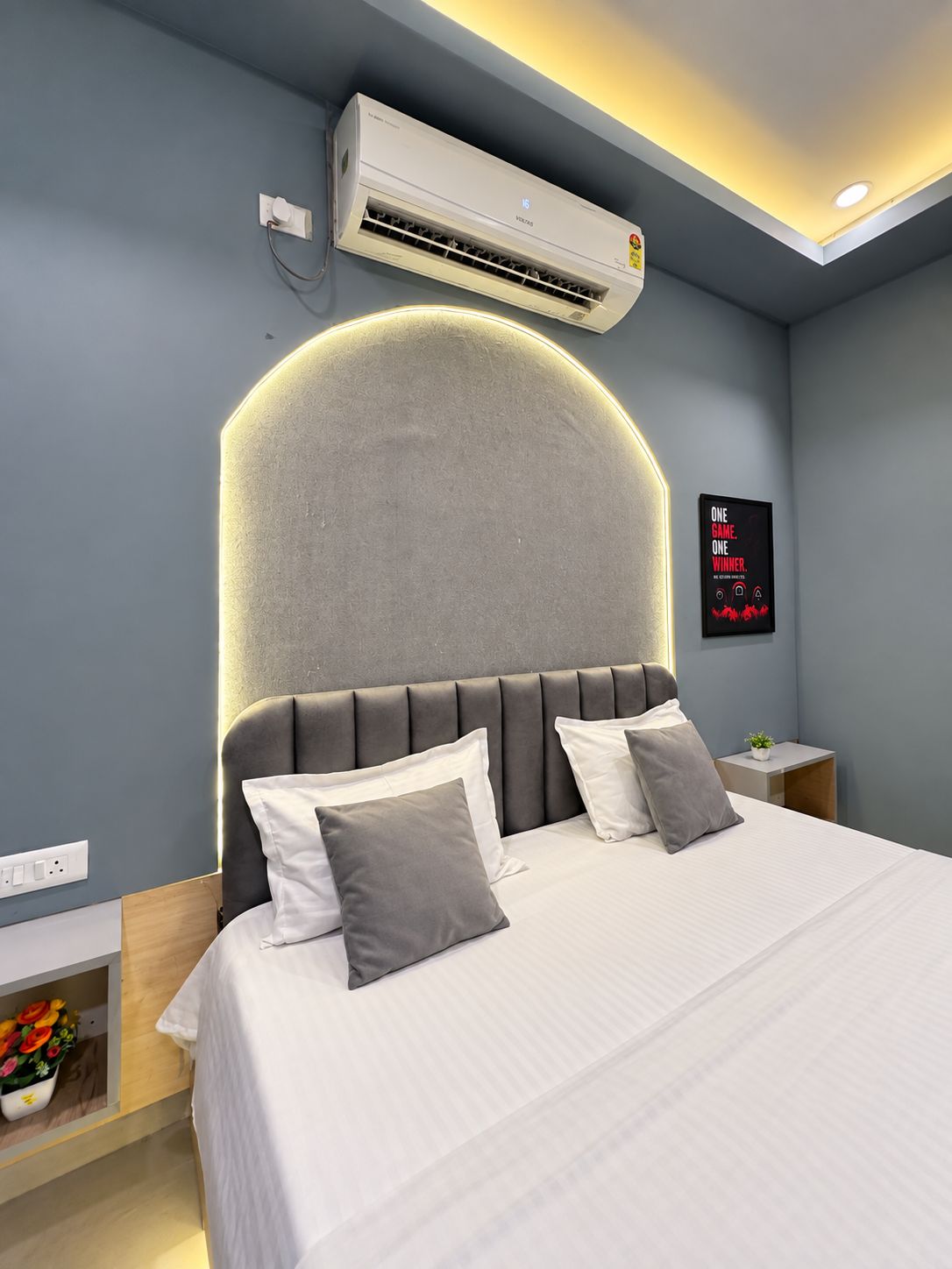 Camera da letto moderna con un letto grande, condizionatore integrato e lampada a parete.