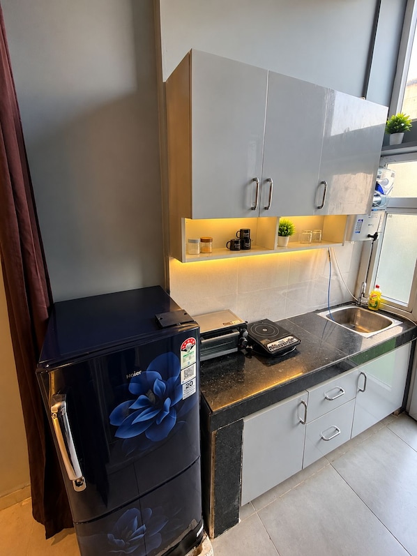 A compact kitchen with a refrigerator, a coffee machine, and a sink.
