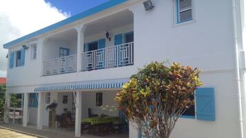 A two-story building with a balcony, a covered porch, and a dining area.