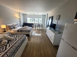 Quarto de hotel com cama, escrivaninha, televisão e frigorífico.