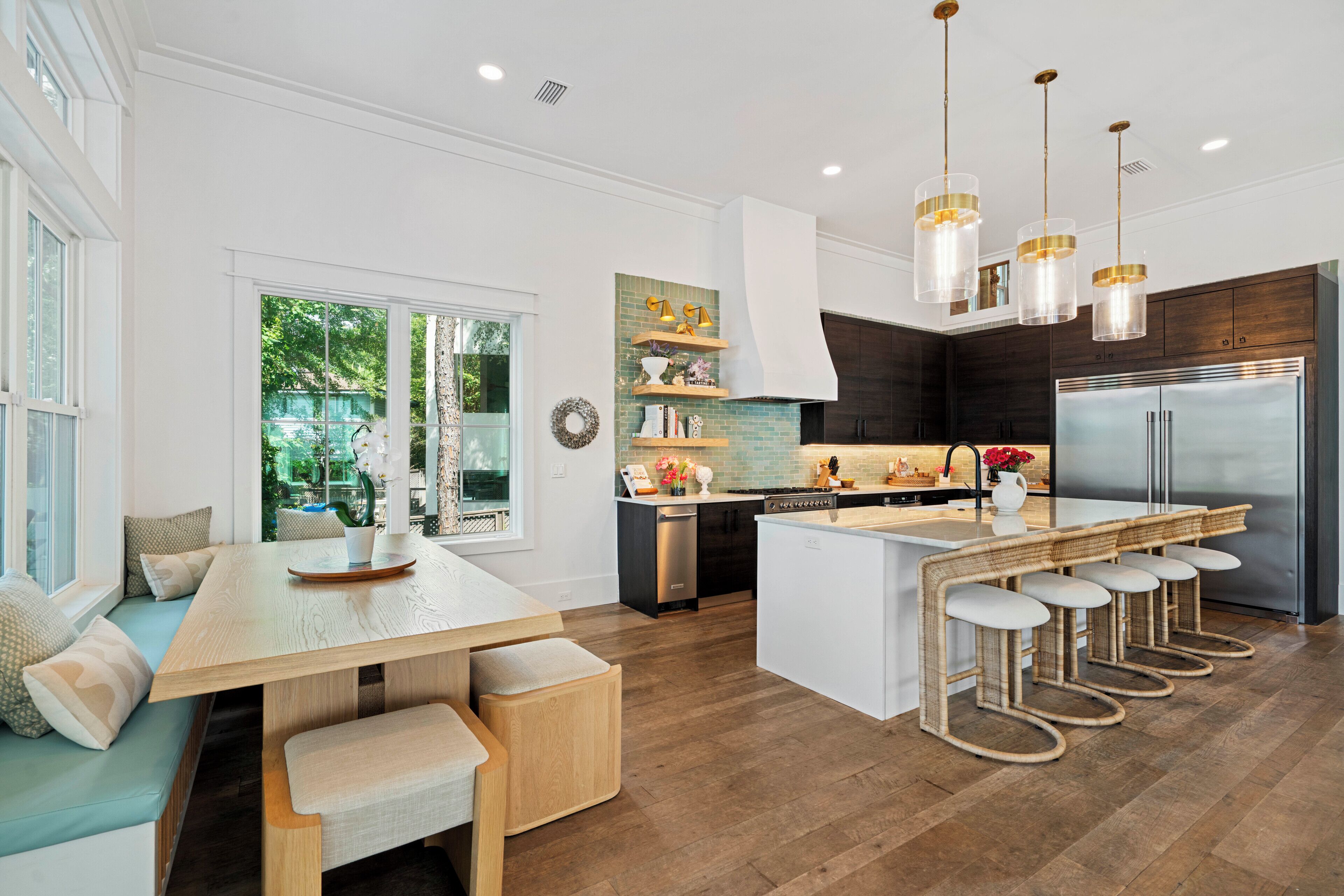 A modern kitchen with a central island, bar stools, and a dining area with a bench.