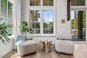 A room with a large window, two cushioned chairs, a wooden coffee table, and a plant. - Luxury on Eastern Lake | Lakefront | Private Pool | 6 Beach Bikes (Santa Rosa Beach)