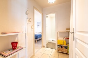 A narrow hallway with a bed, a shelf with books, and a small storage unit. - Capsea - Vue sur le port (Capbreton)