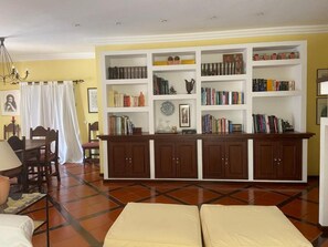 A living room with a sofa set, a dining table with chairs, a bookshelf, and a decorative vase. - Alvor Sun Villa | Private Pool | 4 Bedrooms (Alvor)
