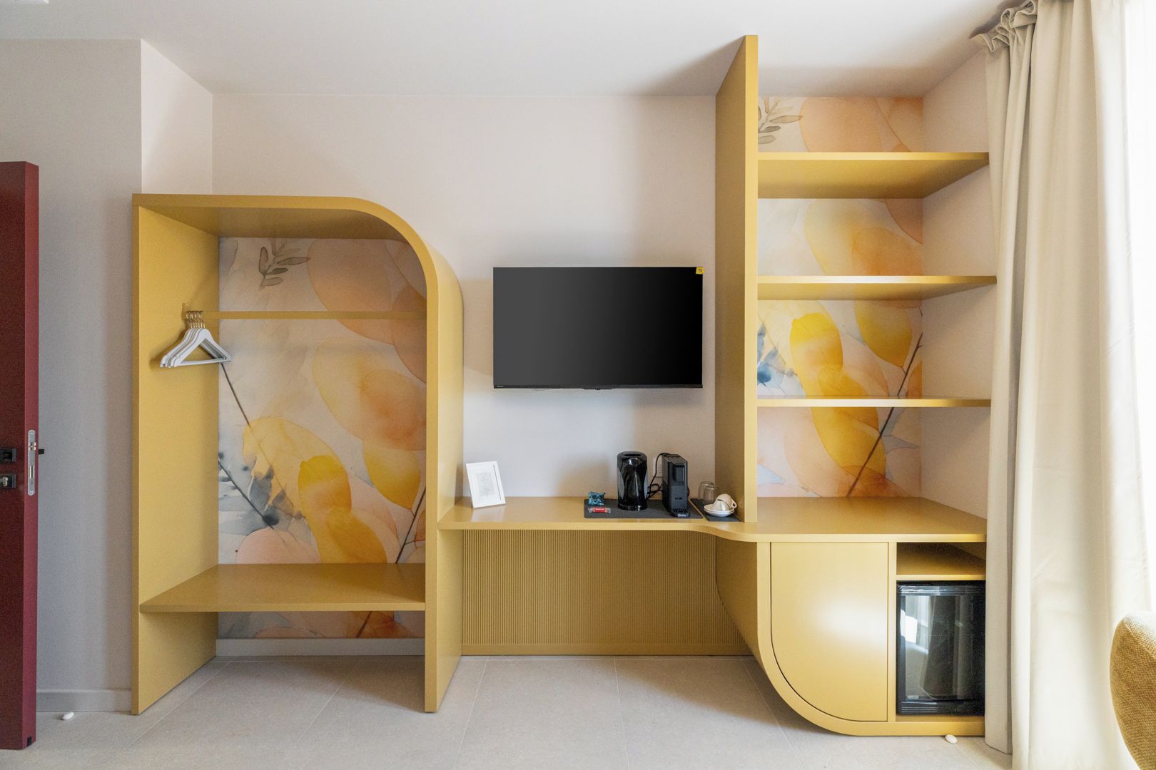 Una habitación moderna con un escritorio curvo, un televisor de pantalla plana y una estantería empotrada.