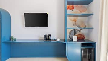 Un soggiorno moderno con un tavolino consolle blu, una TV a schermo piatto montata a parete e uno scaffale decorativo con motivo a conchiglia.