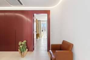 A modern interior with a brown leather sofa, a potted plant, and a red wardrobe.