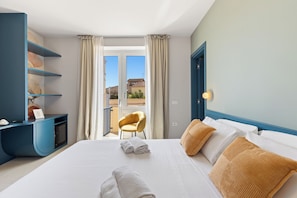 A hotel room with a bed, a desk, a chair, and a view of the outside. - Koro guesthouse (Oristano)