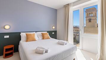 Habitación de hotel con una cama grande, dos almohadas, una mesita de noche y vistas a un edificio a través de una ventana.