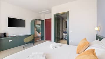 Habitación de hotel con cama, escritorio, silla, televisión y baño visible a través de una puerta abierta.