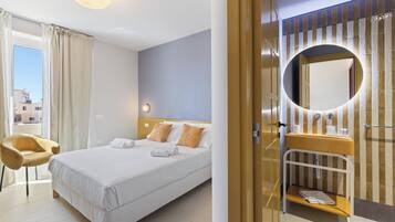 Ein Hotelzimmer mit Bett, Stuhl, Badezimmer mit Spiegel und Blick nach draußen.