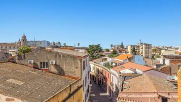 Une rue étroite bordée de bâtiments des deux côtés, un ciel bleu dégagé et une vue lointaine d’une tour.