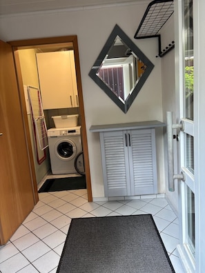 A laundry room with a washing machine, drying rack, and a mirror on the wall. - A thoughtfully furnished vacation rental in Diefenbach (Sternenfels)