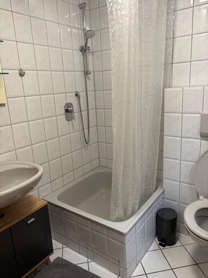 Une salle de bain avec une baignoire, une douche, des toilettes et un lavabo.