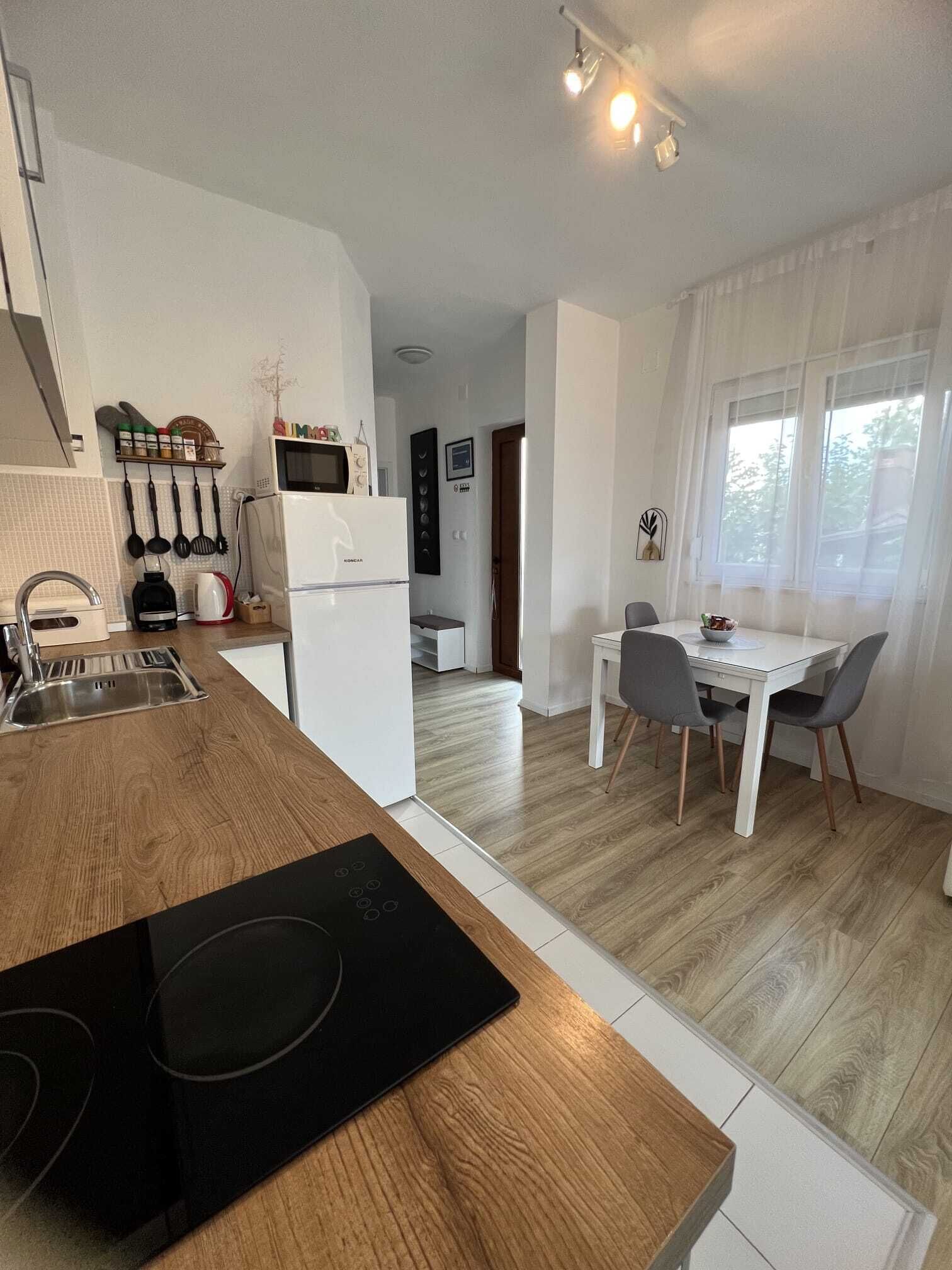 A modern kitchen with a built-in stove, a refrigerator, and a microwave. There is a dining area with a table and chairs.