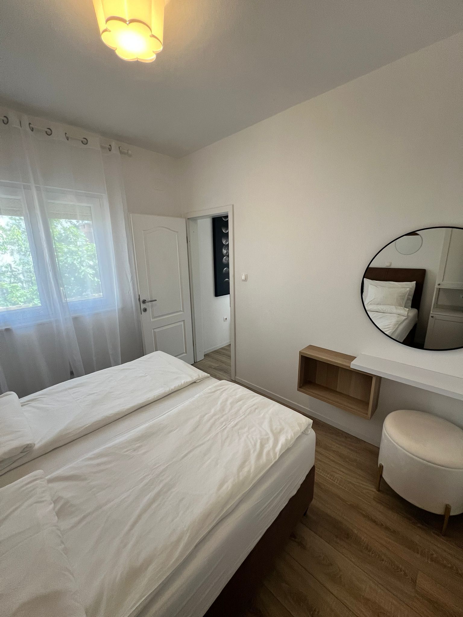 Ein Schlafzimmer mit einem Bett, einem Nachttisch, einem Spiegel und einer Tür zu einem anderen Raum.