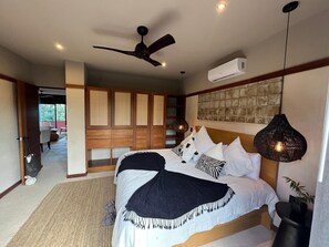 Ein Schlafzimmer mit Bett, Deckenventilator, Klimaanlage und einer Pendelleuchte.