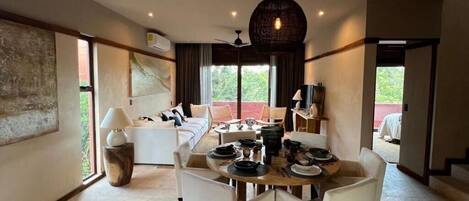 A dining area with a round table, white chairs, and a hanging light fixture.