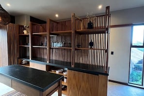 Eine moderne Küche mit Holzschränken, einer schwarzen Arbeitsplatte und eingebauten Regalen.