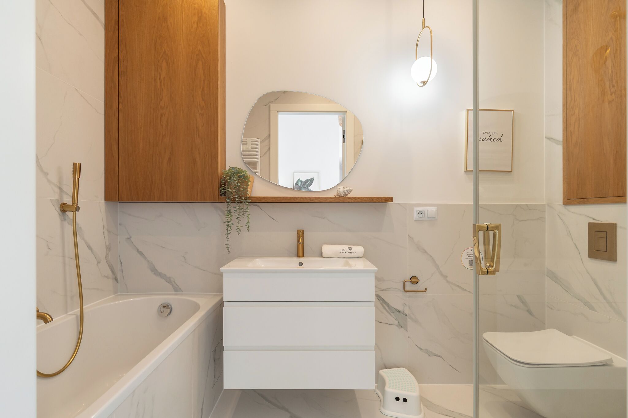 A modern bathroom with a marble vanity, a freestanding bathtub, a toilet, and a glass-enclosed shower area.