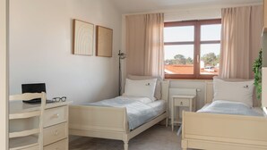 Quarto com duas camas, uma escrivaninha e uma cadeira.