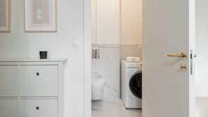 Casa de banho moderna com máquina de lavar roupa, sanita e lavatório.