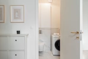 Ett modernt badrum med tvättmaskin, toalett och handfat.