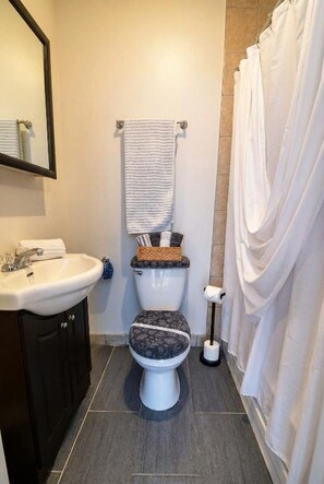 A bathroom with a toilet, sink, and shower curtain. - Mondo Downtown Montreal Studio | Steps from Old Port (Montréal)