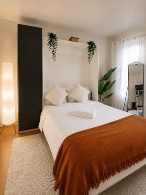 A hotel room with a bed, a bedside lamp, a mirror, and a plant. - Mondo Downtown Montreal Studio | Steps from Old Port (Montréal)