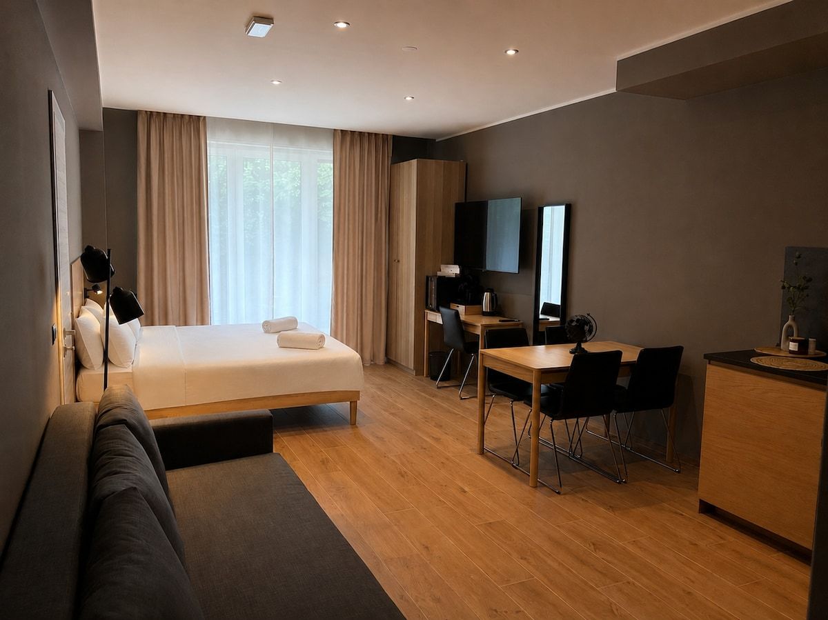 Ein modernes Hotelzimmer mit Bett, Schreibtisch, Sofa und Fernseher.