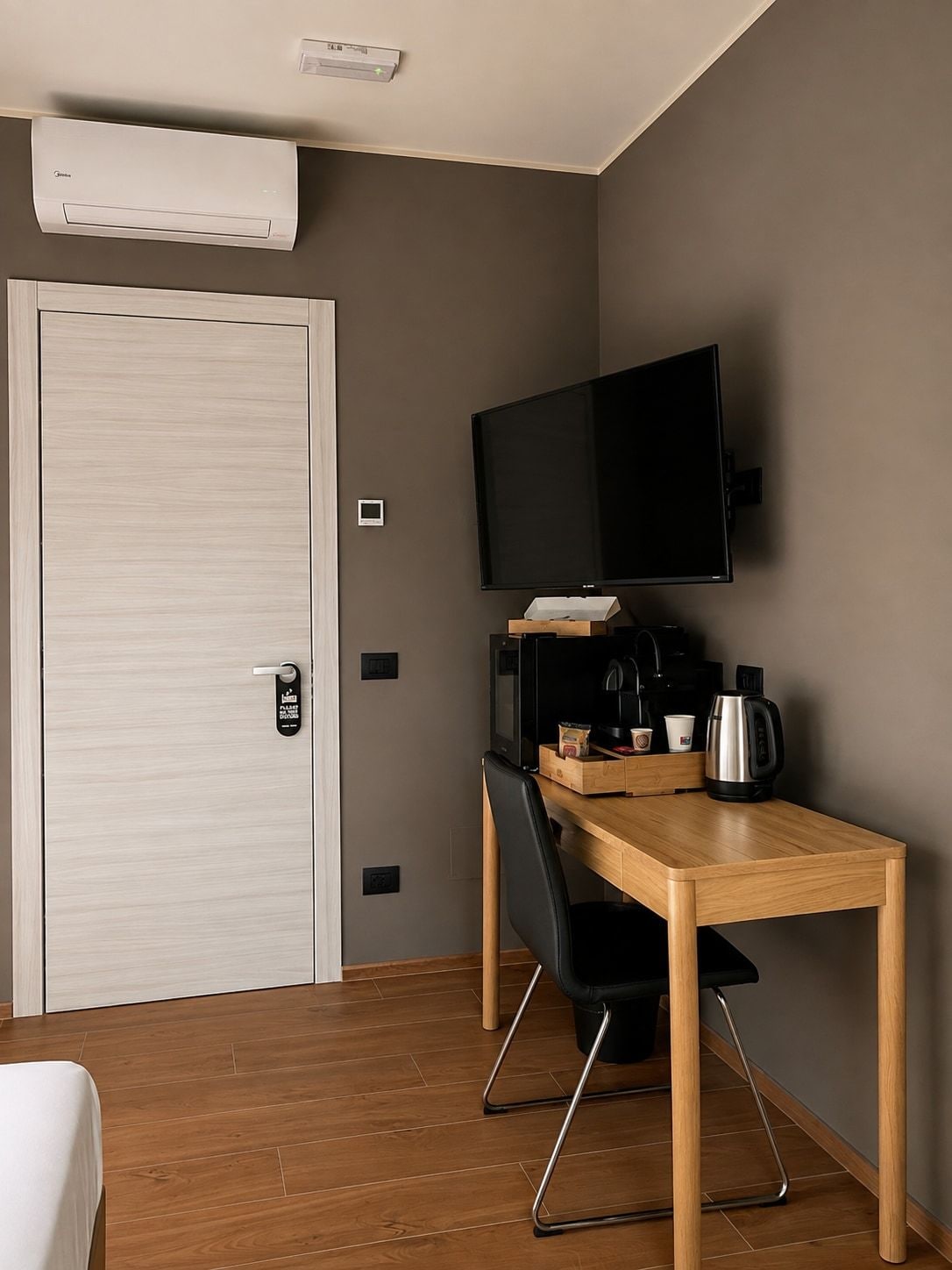 Ein Hotelzimmer mit einem Holztisch, schwarzen Stühlen, einem Fernseher und einer Kaffeemaschine.