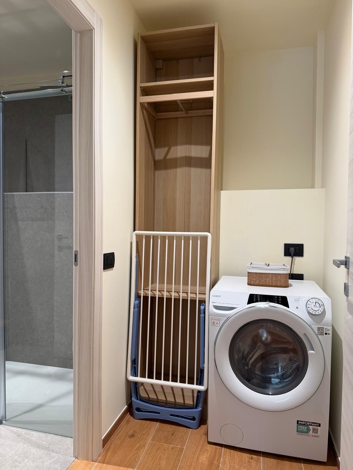 Un espace buanderie équipé d’un lave-linge et d’un étendoir.